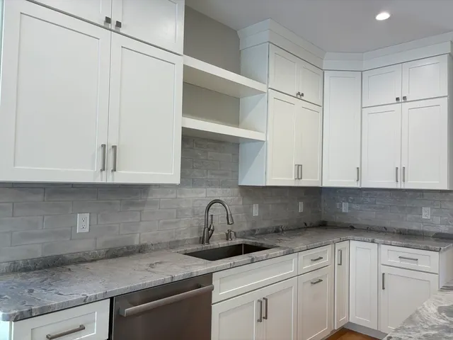 a kitchen with granite countertop white cabinets and a sink
