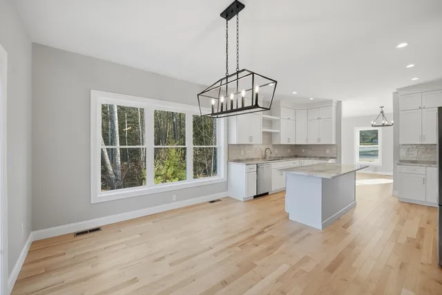 a open kitchen with granite countertop a stove top oven a sink and dishwasher with wooden floor