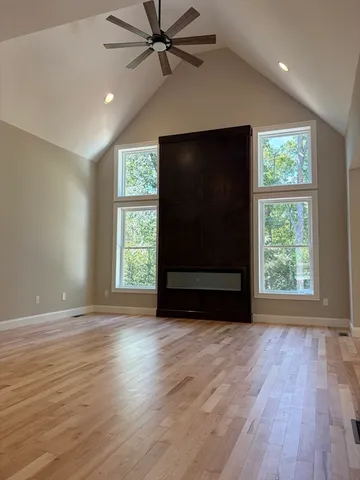 an empty room with wooden floor fan and windows