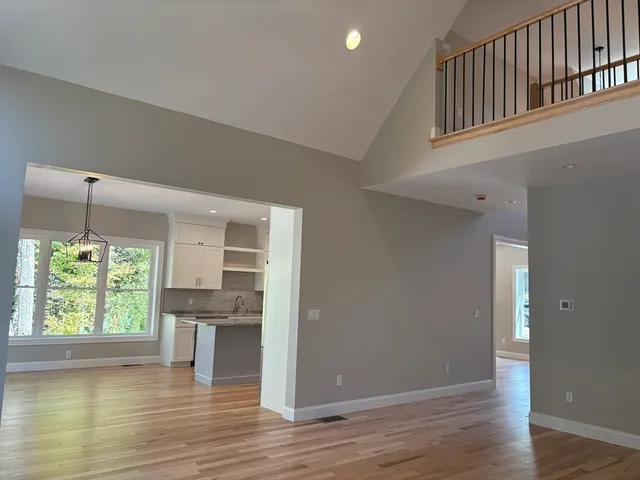 a view of empty room with wooden floor and kitchen view