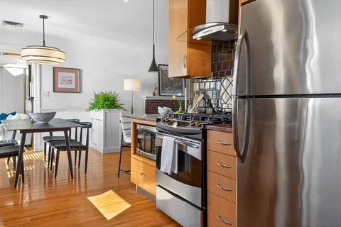 a kitchen with stainless steel appliances granite countertop a refrigerator a stove and a dining table with wooden floor