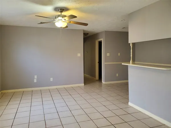 a view of an empty room and chandelier fan
