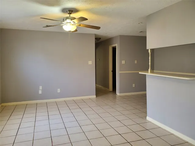a view of an empty room and chandelier fan