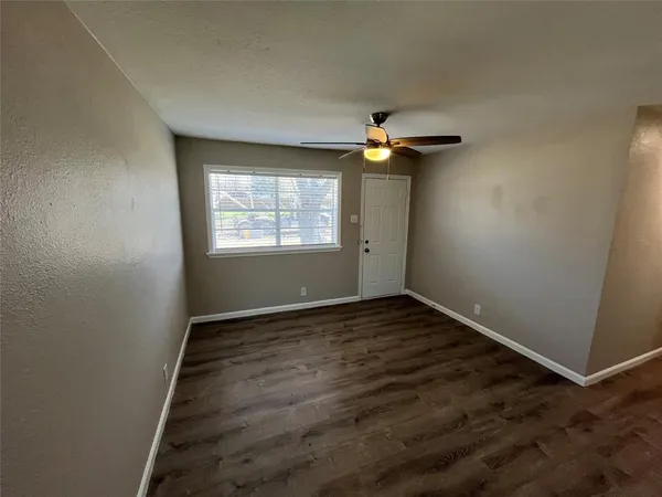 an empty room with windows and chandelier fan