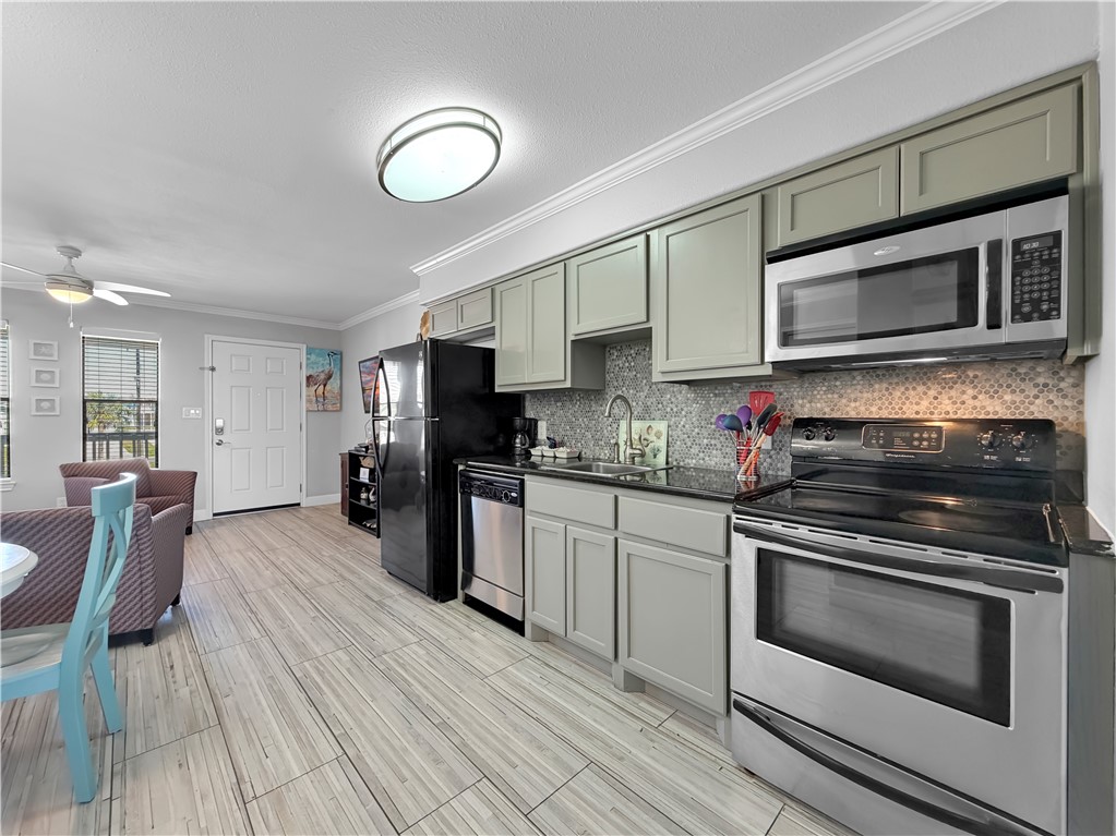 2290 North Fulton Beach Road, Unit 214 Rockport, TX 78382 - Photo 24 of 29 a kitchen with stainless steel appliances kitchen island granite countertop a stove a sink and a microwave
