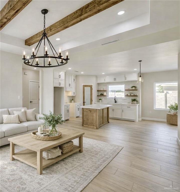 910 Trinity Street Alamo, TX 78516 - Photo 3 of 12 a living room with furniture a rug kitchen view and a chandelier