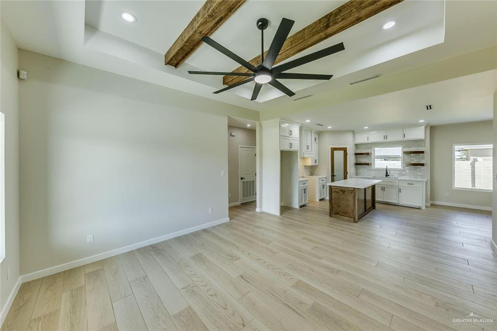 910 Trinity Street Alamo, TX 78516 - Photo 4 of 12 a view of a livingroom with wooden floor a ceiling fan and kitchen space