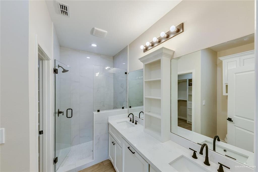 910 Trinity Street Alamo, TX 78516 - Photo 8 of 12 a bathroom with a double vanity sink a large mirror and shower