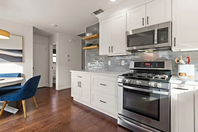 a kitchen with stainless steel appliances a stove a microwave oven cabinets and a wooden floor