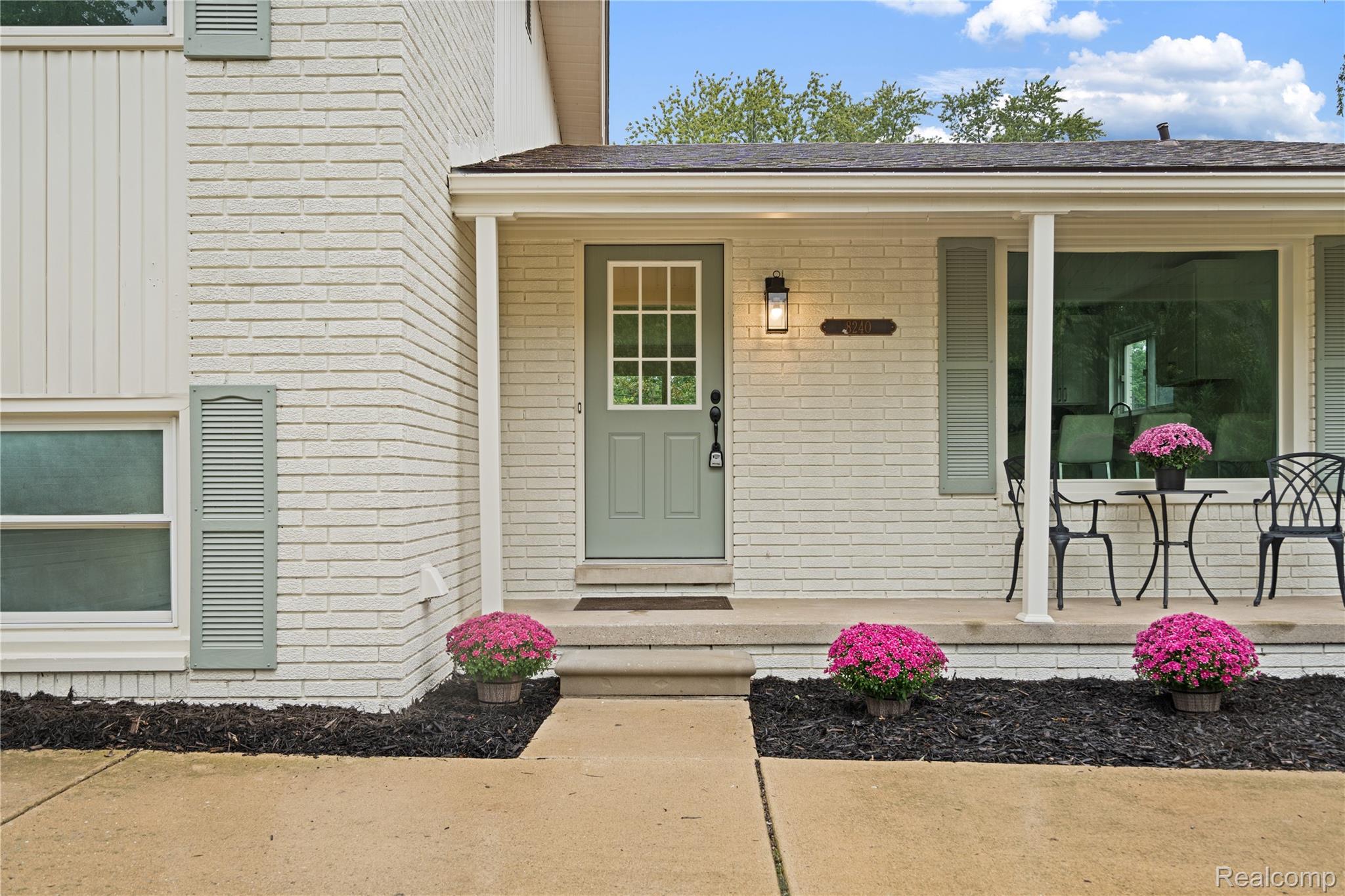 8240 Hampton Road Grosse Ile, MI 48138 - Photo 6 of 33 Painted brick exterior with vertical siding accents, a covered front porch, and a paneled entry door with glass inserts