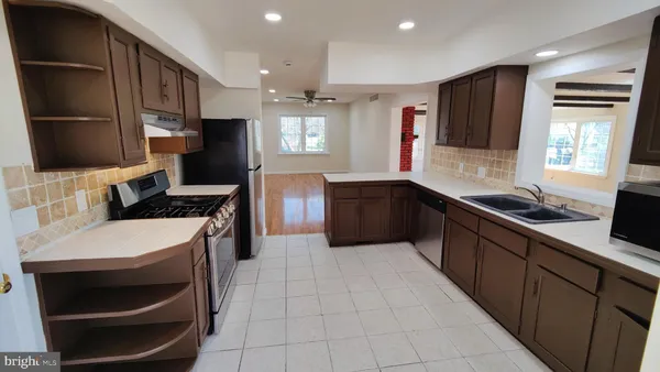 a large kitchen with stainless steel appliances a stove a sink and a refrigerator