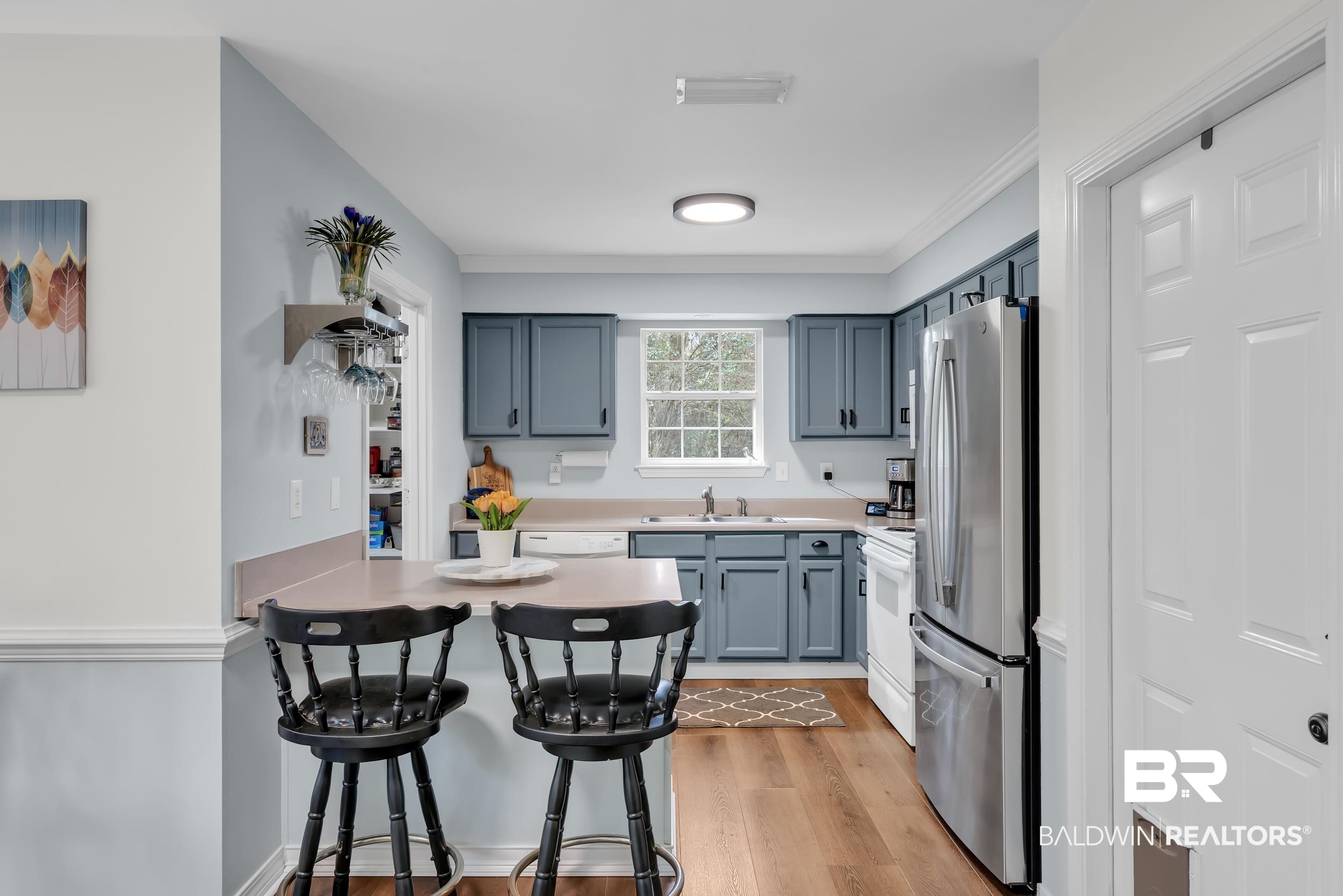191 Robbins Boulevard Daphne, AL 36526 - Photo 8 of 24 Kitchen featuring a kitchen breakfast bar, a peninsula, freestanding refrigerator, light countertops, and light wood-type flooring