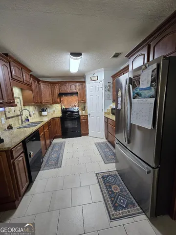 a kitchen with stainless steel appliances granite countertop a refrigerator stove and sink