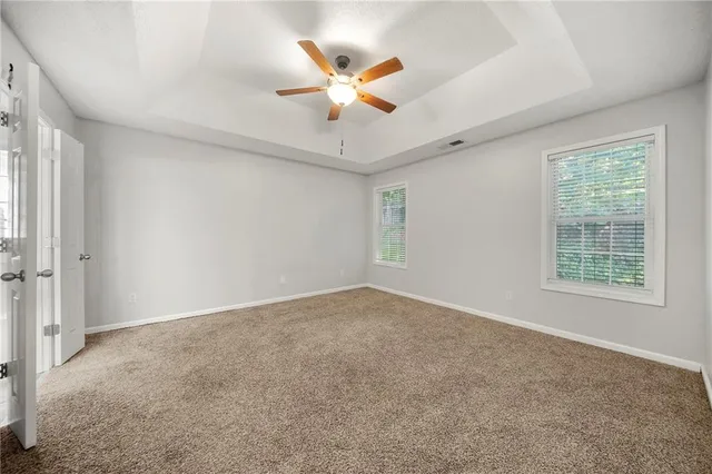 a view of an empty room with a ceiling fan and window