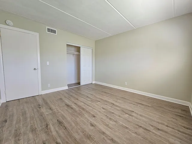 a view of an empty room with wooden floor and closet