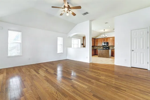 a view of empty room with wooden floor and ceiling fan