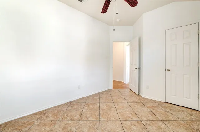 an empty room with ceiling fan and window