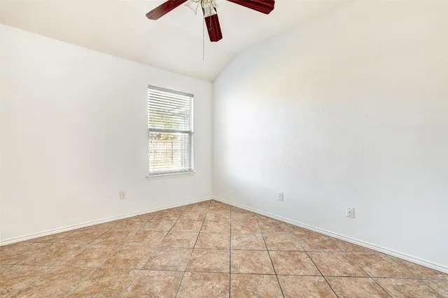 an empty room with ceiling fan and window
