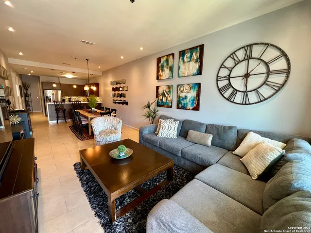 a living room with furniture a table kitchen view and a chandelier