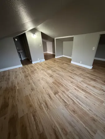 an empty room with wooden floor and painting on the wall