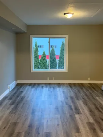 an empty room with wooden floor and chandelier fan