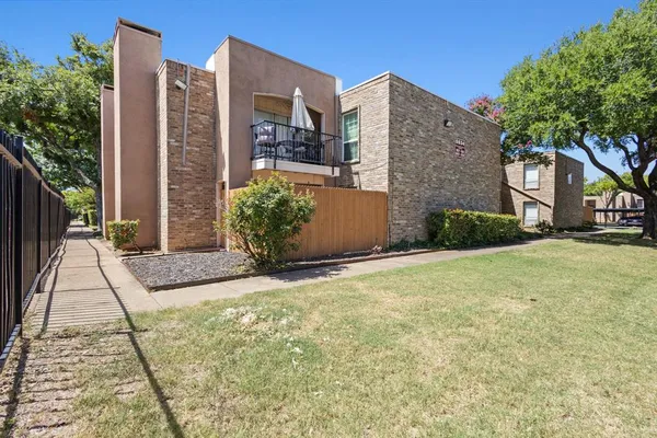 a view of a brick house with a yard and plants
