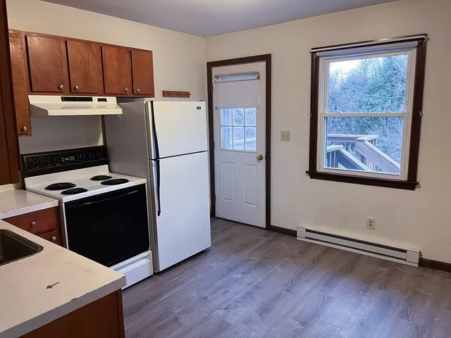 a room with wooden floor and white appliances