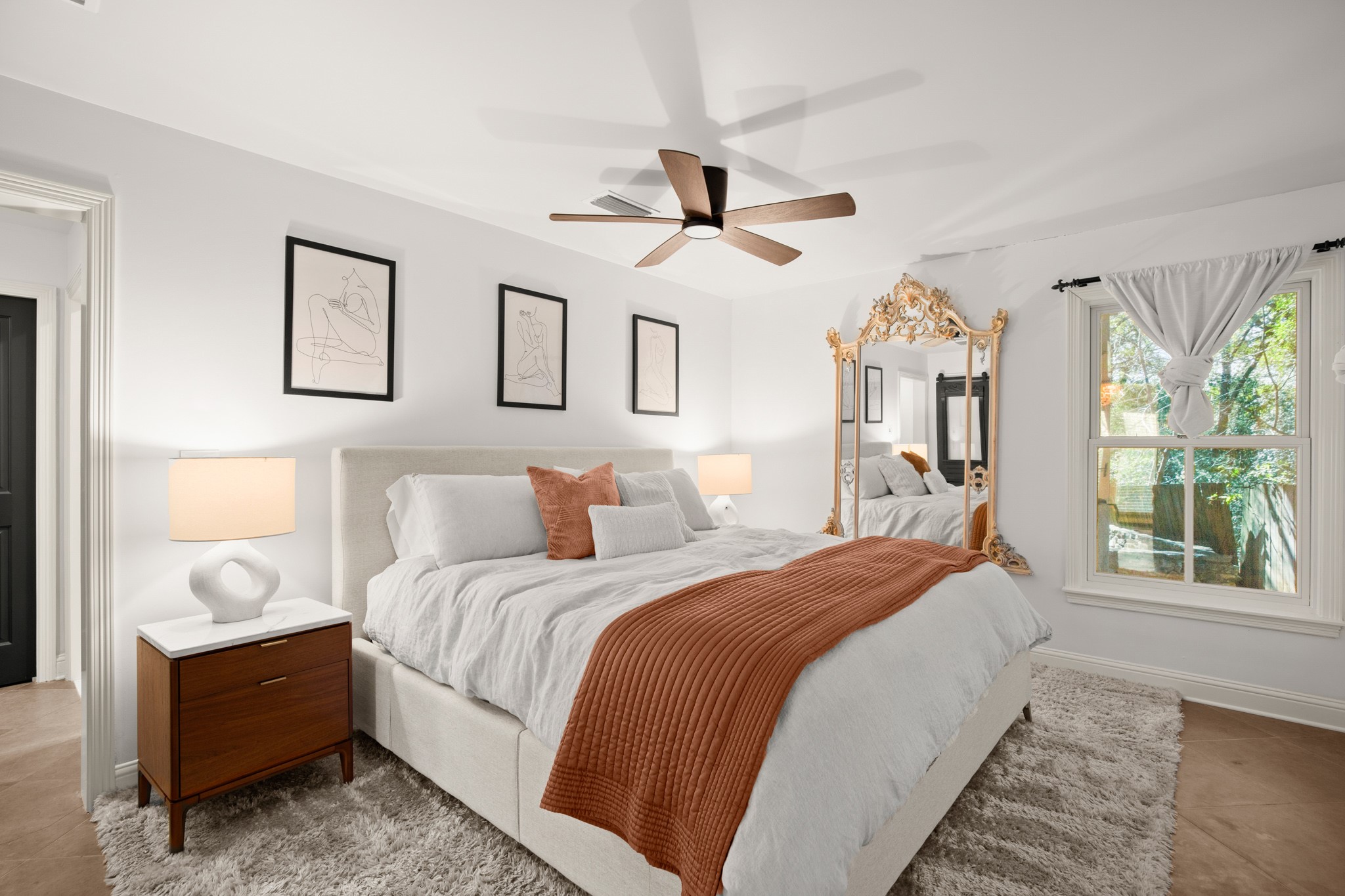 1601 Whitney Way Austin, TX 78741 - Photo 20 of 30 An inviting primary bedroom with clean white walls features a ceiling fan, a large window, and light-colored flooring.