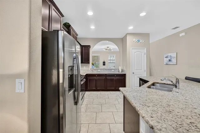 a kitchen with stainless steel appliances granite countertop a sink refrigerator and cabinets