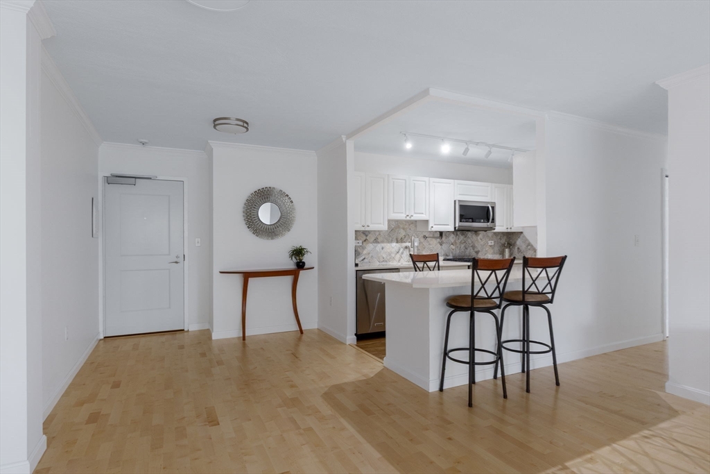 6 Whittier Place, Unit 7E Boston, MA 02114 - Photo 12 of 33 a kitchen with a table chairs refrigerator and microwave