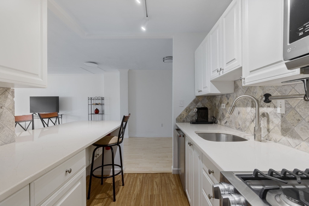 6 Whittier Place, Unit 7E Boston, MA 02114 - Photo 14 of 33 a kitchen with stainless steel appliances granite countertop a sink a stove and a refrigerator