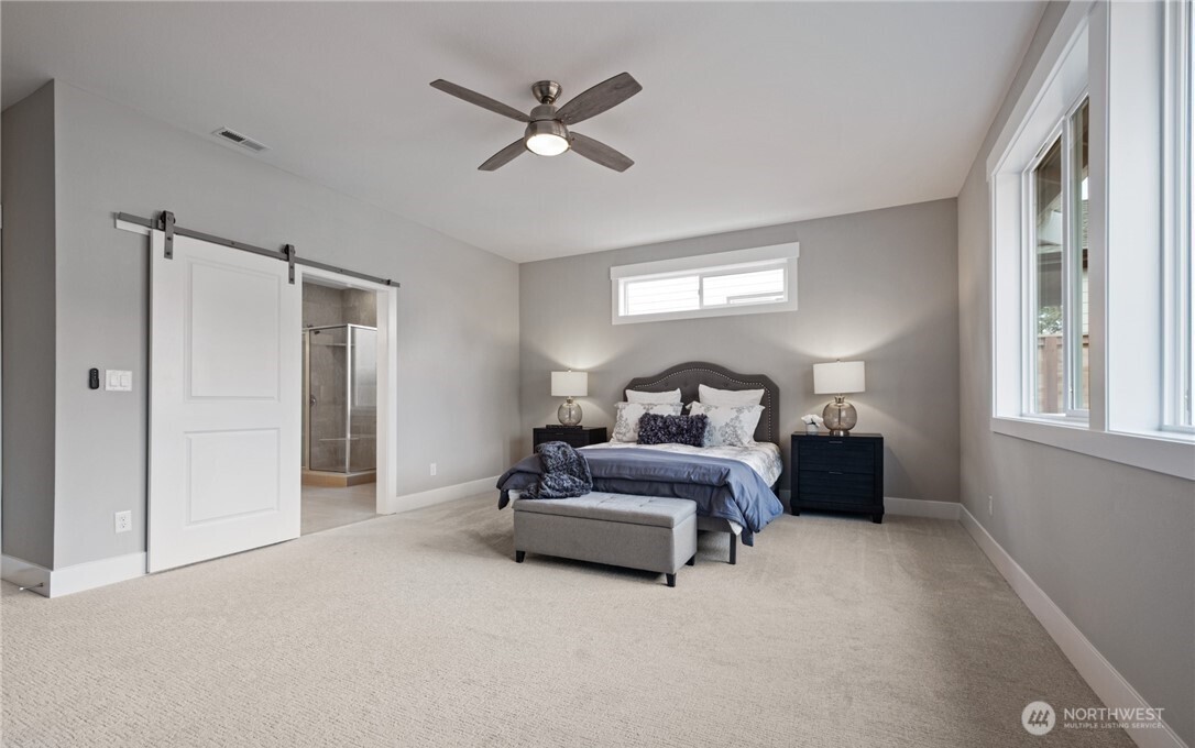 8831 27th Street East Edgewood, WA 98371 - Photo 18 of 27 a spacious bedroom with a bed and a chandelier
