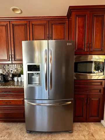 a kitchen with stainless steel appliances granite countertop a refrigerator a stove and a sink