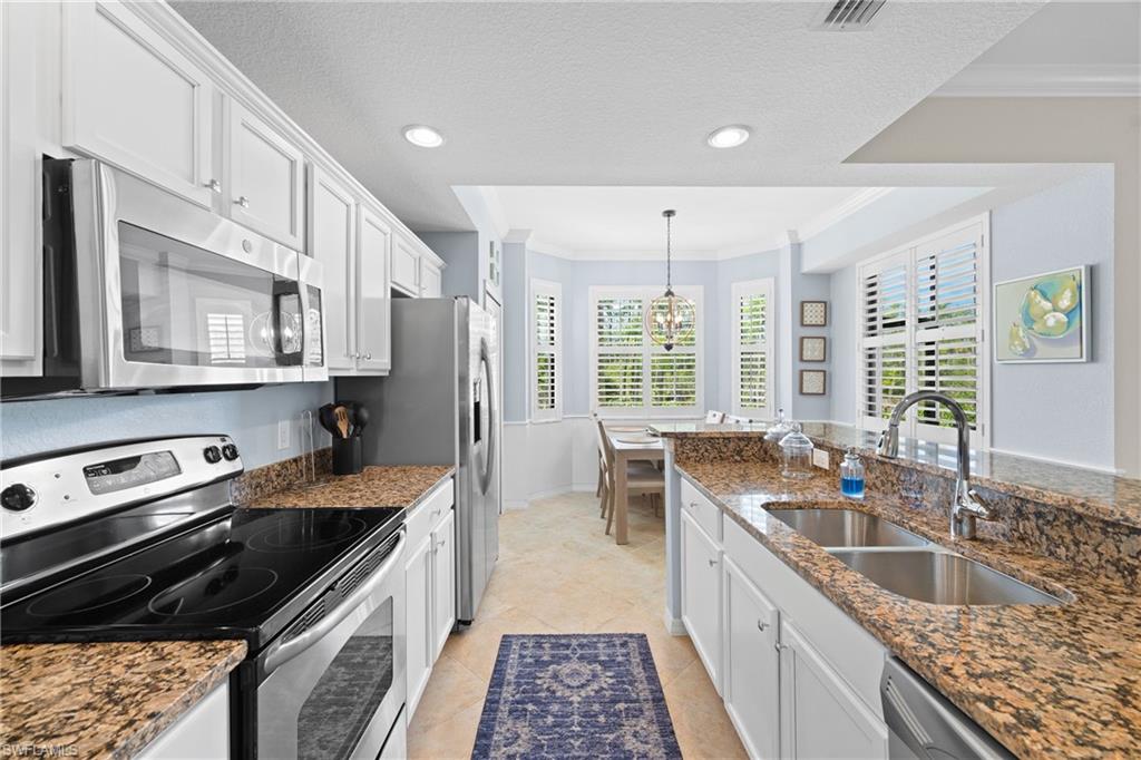 9715 Acqua Court, Unit 116 Naples, FL 34113 - Photo 9 of 43 a kitchen with stainless steel appliances granite countertop a sink stove and cabinets
