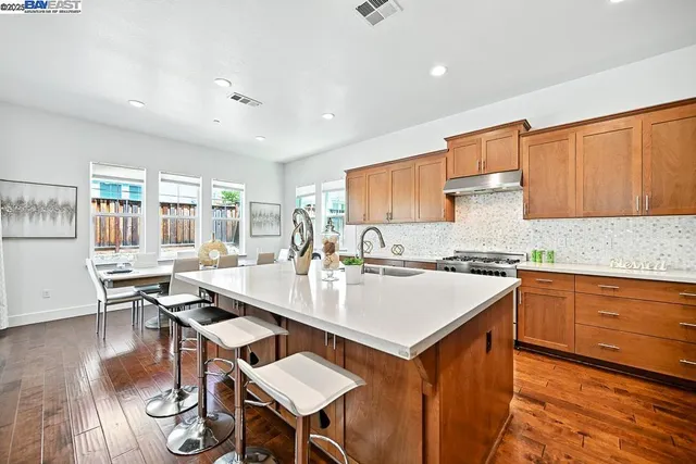 a kitchen with stainless steel appliances granite countertop a table chairs sink refrigerator and cabinets