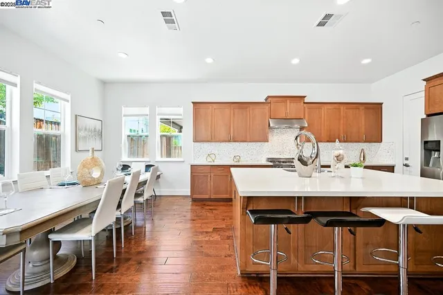 a view of a kitchen with kitchen island a stove a sink a refrigerator and wooden cabinets