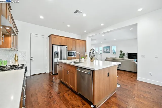 a open kitchen with stainless steel appliances granite countertop a sink and living room view