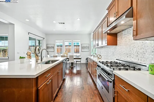 a living room with stainless steel appliances furniture a dining table and kitchen view