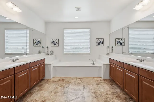 a bathroom with a sink double vanity granite tub shower and a mirror