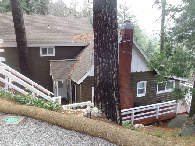 a view of a house with a yard and large tree
