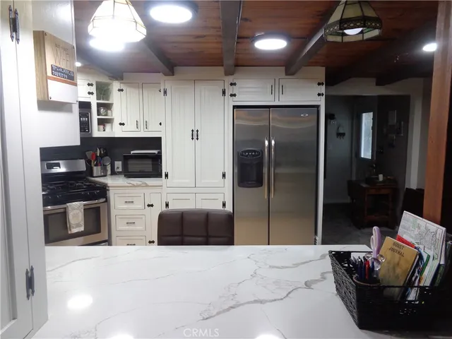 a kitchen with stainless steel appliances kitchen island granite countertop a refrigerator a sink a stove and cabinets