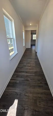 a view of a refrigerator in kitchen and an empty room with wooden floor