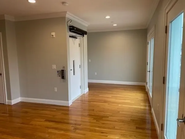 a view of an empty room with wooden floor and a window