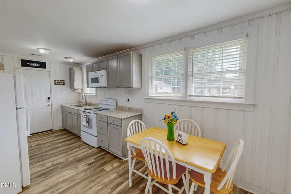 a kitchen with stainless steel appliances granite countertop a stove top oven a sink dishwasher a dining table and chairs with wooden floor