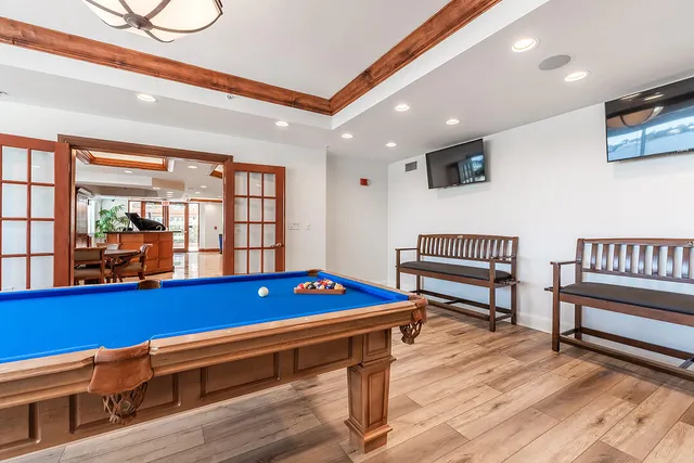a room with wooden floor pool table furniture and windows