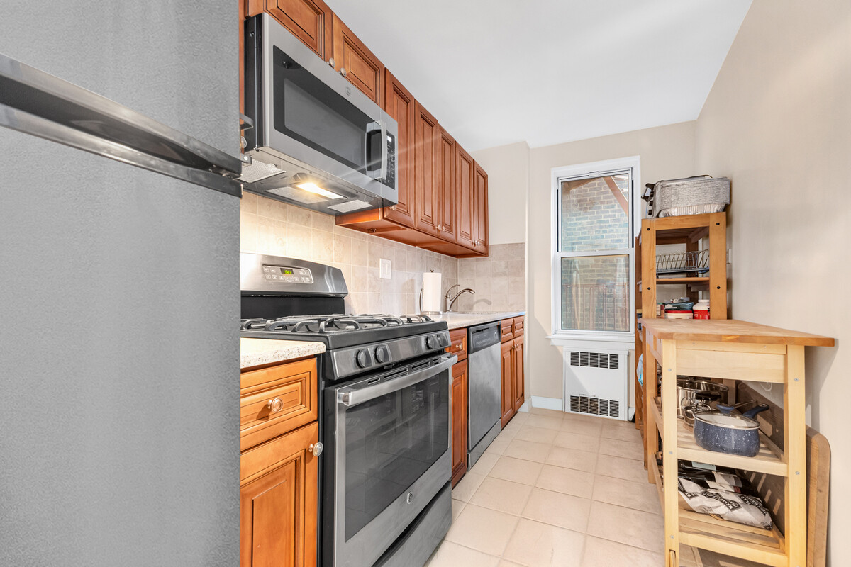 67-07 Yellowstone Boulevard, Unit 3H Queens, NY 11375 - Photo 4 of 6 a kitchen with stainless steel appliances granite countertop a stove and a refrigerator