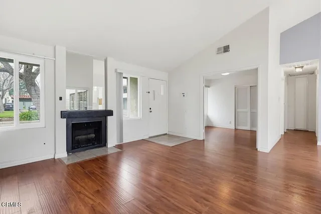 an empty room with wooden floor fireplace and windows