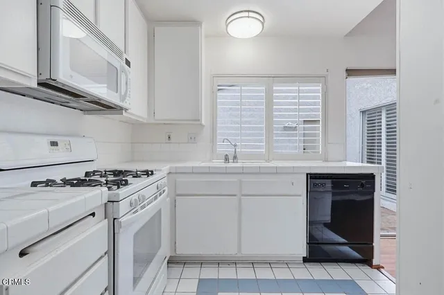 a kitchen with granite countertop white cabinets and white appliances