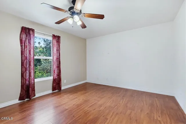 a view of an empty room with window and wooden floor