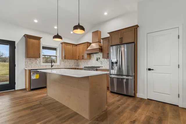 a large kitchen with stainless steel appliances granite countertop a refrigerator a oven a sink and a wooden floors